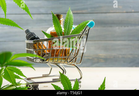 Chariot de supermarché avec des feuilles de marijuana médicale et de l'huile de cannabis cbd Banque D'Images