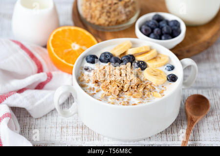 Bol de céréales de petit-déjeuner avec des bananiers et les bleuets sur table en bois blanc. Vue rapprochée. Concept de petit-déjeuner sain, d'une saine alimentation Banque D'Images