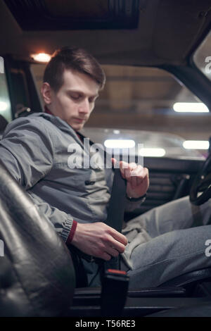 Photo de côté conducteur homme ceinture de fixation en position assise, dans une voiture sur l'assurance-métro Banque D'Images