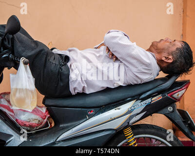 Prendre un pilote moto vietnamienne reste sur sa moto dans une rue de Ho Chi Minh Ville, Vietnam. Banque D'Images