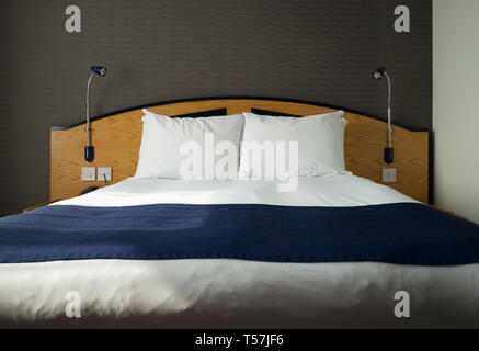 Des lit double avec oreillers, draps et literie à Holiday Inn Express, avec la lumière du soleil diffusée à partir de la fenêtre à proximité Banque D'Images