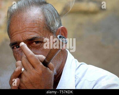 Les Indiens d'âge moyen homme Rajasthani fume du tabac dans sa pipe chillum en public. Banque D'Images