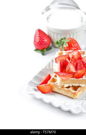 Belgique waffers avec du sucre en poudre et les fraises sur une plaque en céramique sur le tableau blanc. Des wafers. Banque D'Images