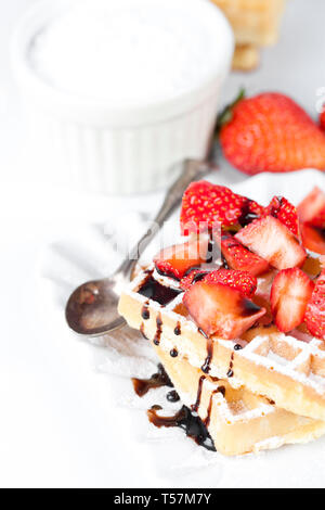 Belgique waffers avec du sucre en poudre, des fraises et du chocolat sur une plaque en céramique sur le tableau blanc. Des wafers. Banque D'Images