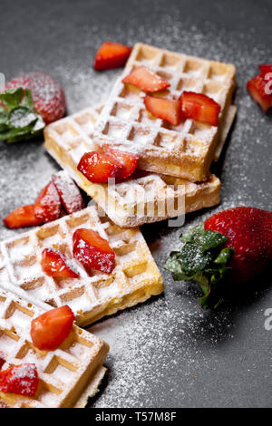 Belgique waffers avec des fraises et du sucre en poudre sur tableau noir l'arrière-plan. Banque D'Images