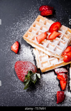 Belgique waffers avec des fraises et du sucre en poudre sur tableau noir l'arrière-plan. Banque D'Images