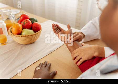 Veste blanche Infirmière en mettant deux doigts sur le poignet du patient Banque D'Images