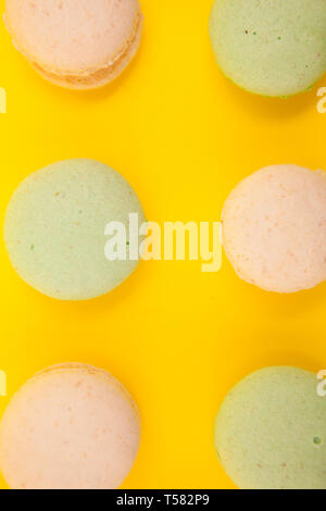 Peach et vert macarons en rangées sur le fond jaune. Dessert de luxe Banque D'Images