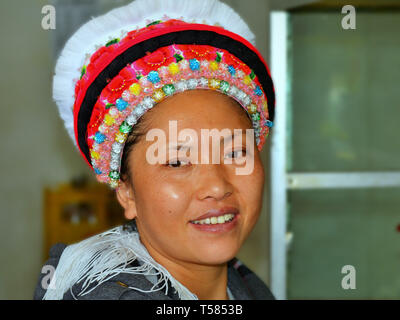 Jeune femme chinoise Bai (minorité ethnique chinoise) avec une coiffure traditionnelle Bai sourit à la caméra. Banque D'Images