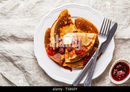 Des crêpes à la confiture de framboises et de beurre sur une assiette blanche, vue du dessus. Banque D'Images