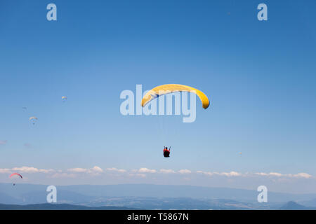 Les hommes voler en parapente dans le ciel bleu, un jour ensoleillé Banque D'Images