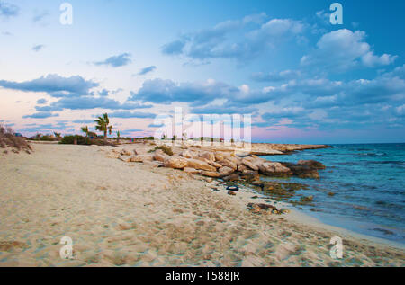 Image de Landa à couper le souffle dans la plage Agia Napa, Chypre. Jaune sable et cailloux contre l'eau bleu calme avec de petites vagues sur une chaude soirée à l'automne, s Banque D'Images