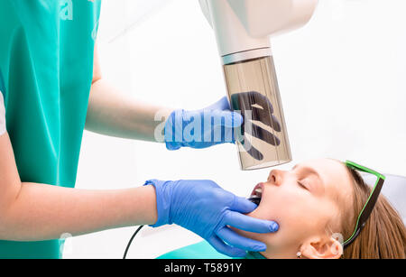 Manipulateur en radiologie à dents prenant de l'âge primaire girl using digital x-ray machine en clinique dentaire pédiatrique. Médecin faisant des rayons X, tandis que Banque D'Images