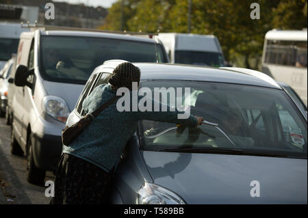 Vieille Femme lave-vitres de voiture et la mendicité des pilotes pour l'argent. Londres. 16/10/2008 Banque D'Images