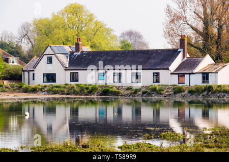 L'École nationale de 1834 transformée en une maison reflète dans le ruisseau à marée haute. Bosham, Chichester, West Sussex, Angleterre, Royaume-Uni, Angleterre Banque D'Images