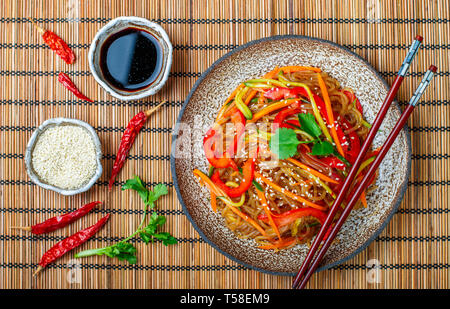 L'amidon (pomme de terre), de riz avec légumes nouilles - poivrons, carottes, concombre, graines de sésame, de la coriandre et de la sauce de soja. Plat végétarien. Un délicieux lu Banque D'Images