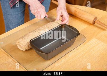 Femme de pain roulé de fraisage pâte multigrains, de sorte qu'il est adapté à la casserole. (MR) Banque D'Images