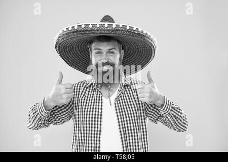 Tenue de fête mexicaine guy heureux prêt à célébrer. L'homme gai barbu guy porter chapeau mexicain sombrero fond jaune. Parti mexicain concept. Maison de vacances traditionnelle mexicaine en fête. Vous permet d'avoir du plaisir. Banque D'Images