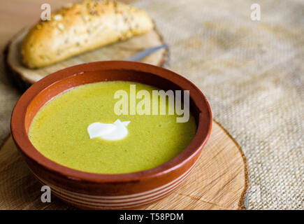 Brocoli soupe de légumes verts bio dans un bol en céramique. Plaque de bois avec de délicieux croûtons de pain. Alimentation biologique, végétalien plat. Banque D'Images