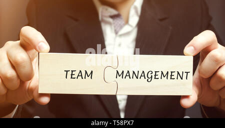 Businessman recueille des puzzles avec les mots de la gestion d'équipe. Accroître l'efficacité. L'embauche et le licenciement des employés. Organisation de l'entreprise de travail pro Banque D'Images