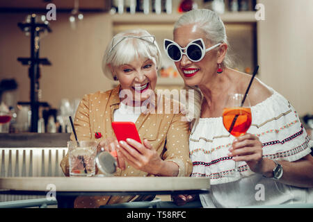 Belle femme d'âge mûr montrant une photo sur son téléphone Banque D'Images