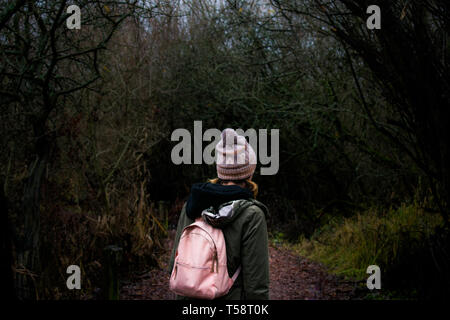Fille dans le sac à dos et beanie marche sur chemin à travers la nuit sombre bois spooky Banque D'Images