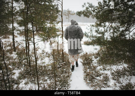 Une femme marche à travers une forêt d'hiver Banque D'Images