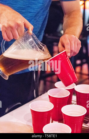 Boy pouring beer de cruche dans red cup au parti de la fraternité Banque D'Images
