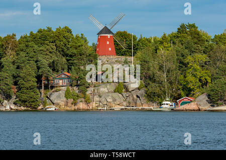 Un traditionnel moulin rouge vif se trouve au sommet d'un affleurement rocheux au-dessus d'une baie dans l'archipel de Stockholm Banque D'Images