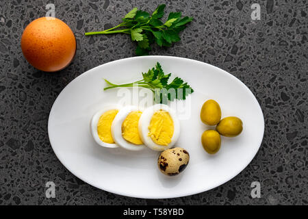 Oeufs de poulet bouilli avec des oeufs de cailles, d'olive et le persil sur la plaque blanche, des aliments sains Banque D'Images