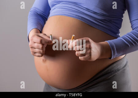 Image de femme enceinte à cesser de fumer sur fond gris. Banque D'Images