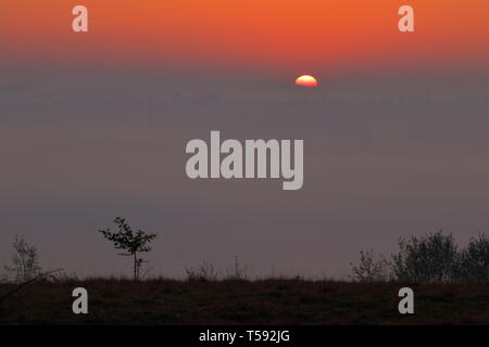 Le soleil apparaît à l'horizon pendant un lever de soleil brumeux depuis le parc national de Rothwell à Leeds, West Yorkshire Banque D'Images