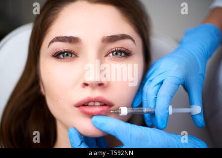 L'augmentation des lèvres. Gros plan du médecin coiffeur beauté faisant mains Procédure pour les lèvres avec seringue. Jeune bouche de femme recevant de l'acide hyaluronique Banque D'Images