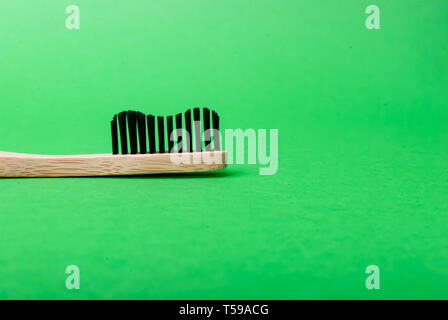 Close up Vue de côté de la tête d'une brosse à dents en bambou sur fond vert with copy space Banque D'Images