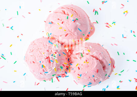 Vue du haut de trois baies rose boules de crème glacée sundae couverts et parsemé saupoudre sur fond blanc Banque D'Images