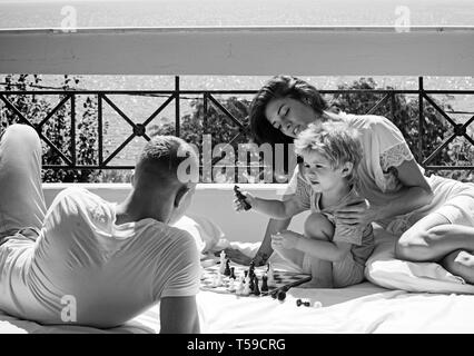 Young Beautiful woman smiling au garçon qui jouait aux échecs avec son père. Banque D'Images