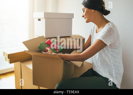 Femme ouvre boîte en carton ou un colis lors d'une nouvelle maison. Présent, déménagement, vacances, boîtes de carton Banque D'Images