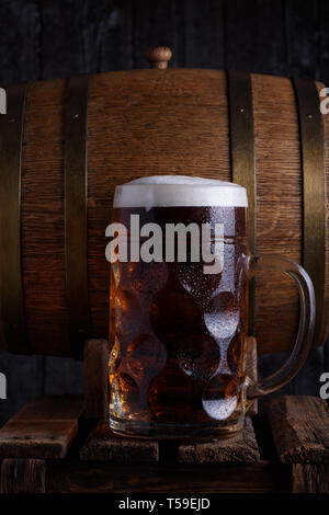 Beer mug énorme sur de vieilles caisses en bois avec vintage beer barrel sur arrière-plan foncé, still life Banque D'Images