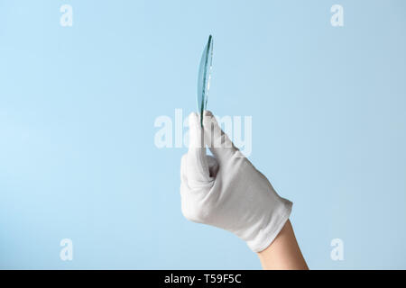 Nouvelles fonctionnalités de recherche de verre, hand in glove holding circle morceau de matériau transparent Banque D'Images