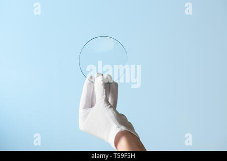 Nouvelles fonctionnalités de verre ou plastique, recherche hand in glove holding circle morceau de matériau transparent Banque D'Images