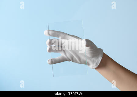 Nouvelles fonctionnalités de recherche en verre ou en plastique, hand in glove holding morceau rectangulaire matière transparente Banque D'Images