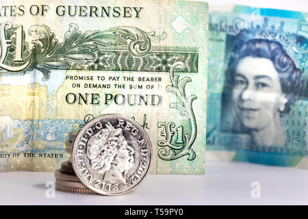 Une pièce de cinq pence avec l'image d'Elizabeth II sur un billet d'une livre de Guernesey et un flou cinq livres de UK Banque D'Images