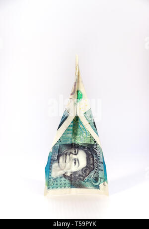 Un nouveau billet de cinq livres (polymère de UK avec la forme d'un avion en papier isolés sur fond blanc, Brexit concept. Banque D'Images