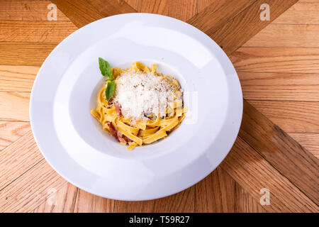 Les pâtes Carbonara classique, spaghetti à la pancetta, bacon, oeufs, fromage parmesan et roquette vert sur table en bois. Banque D'Images