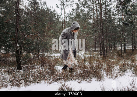 Une femme marche à travers les bois en hiver Banque D'Images