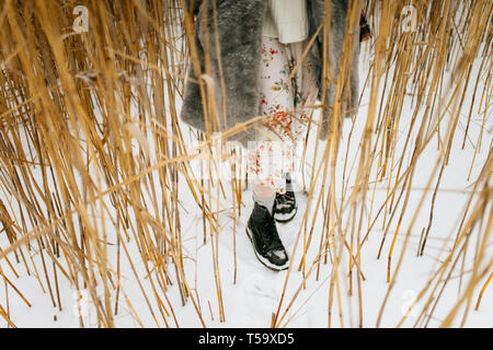 Pieds d'une femme marche sur l'herbe sèche en hiver Banque D'Images