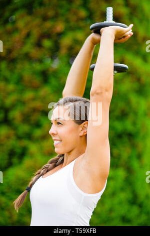 Smiling pregnant woman doing Triceps Exercice Extension In Park Banque D'Images