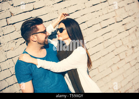 Jeune couple heureux en amour posant contre mur. Banque D'Images
