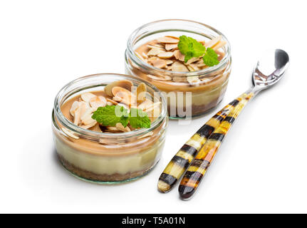 Mini cheesecakes au caramel dans un pot de verre isolé sur fond blanc Banque D'Images