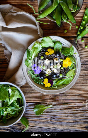 Haricots noirs végétarien salade de légumes verts, olives, petits pois, fromage de brebis, décoré avec des fleurs comestibles Banque D'Images